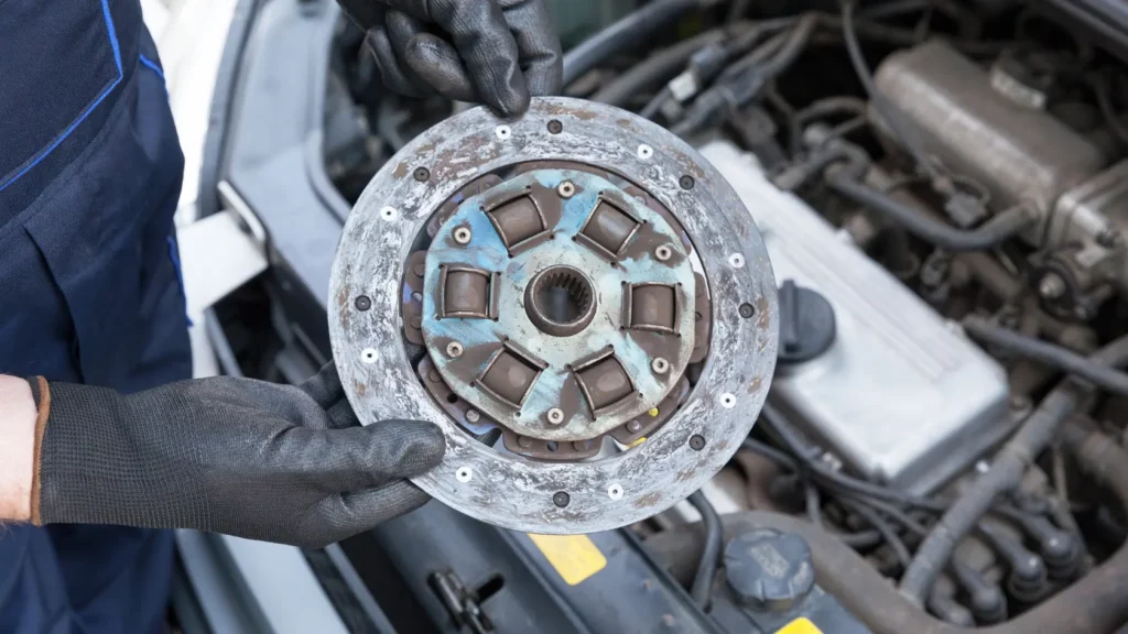 vehicle technician holding a worn clutch disc